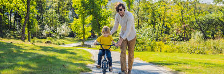 Father teaches his son ride a bicycle.の写真素材