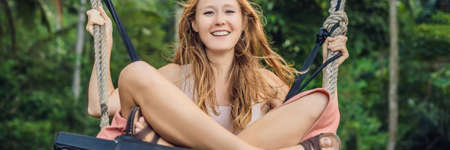 Young tourist woman on the swing in the jungle rain forest of a tropical Bali island.の写真素材