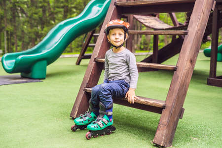 A boy in roller skates on the playground. The boy learns to ride roller skates the first day and is tired.の写真素材