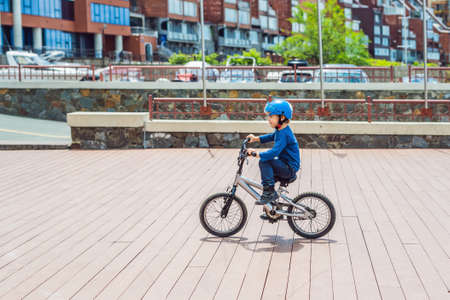 Happy kid boy having fun near the yacht club with a bicycle on beautiful day. Active child wearing bike helmet.の写真素材