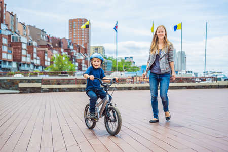 Mom teaches son to ride a bike in the park.の写真素材