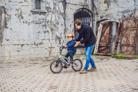 Dad teaches son to ride a bike in the park.の写真素材