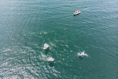 Aerial drone photo of young teenagers on small sailing boats competing in the regatta at...