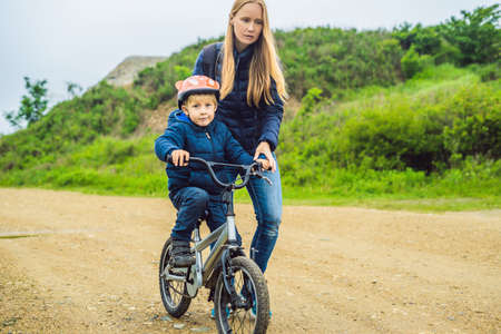 Mom teaches son to ride a bike in the park.の写真素材