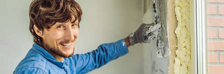 Master is applying white putty on a wall and smearing by putty knife in a room of renovating house...
