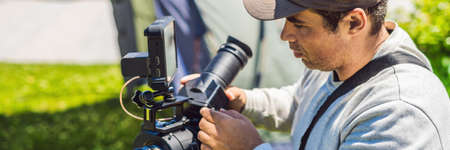 A professional cameraman prepares a camera and a tripod before shooting