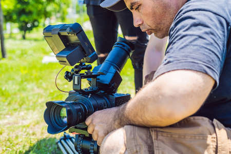 A professional cameraman prepares a camera and a tripod before shooting