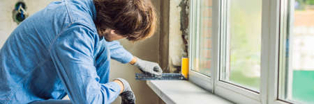 Man in a blue shirt does window installationの写真素材