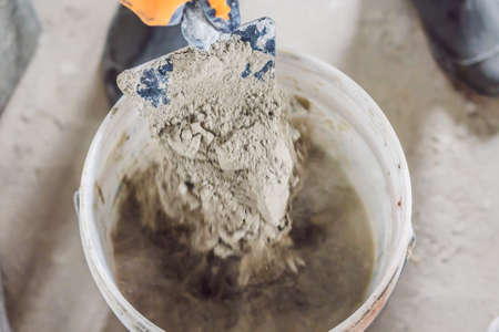 Man making cement with a construction mixer in a bucket.の写真素材