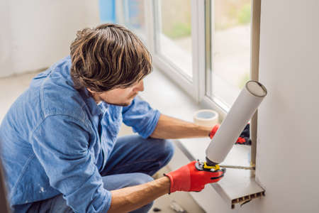 Man in a blue shirt does window installation.