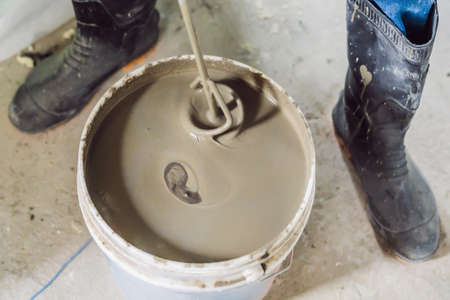 Man making cement with a construction mixer in a bucket.の写真素材