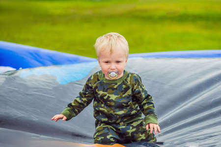 Little boy enjoying jumping on trampoline summer day outside.の写真素材