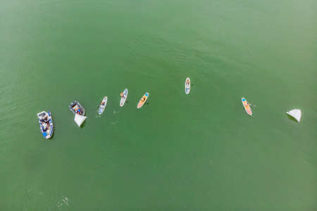 Strong men floating on a SUP boards in a beautiful bay on a sunny day. Aerial view of the men crosses the bay using the paddleboard. Water sports, competitions.の写真素材