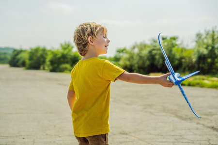 Happy kid playing with toy airplane against old runway background. Traveling with kids concept.の写真素材