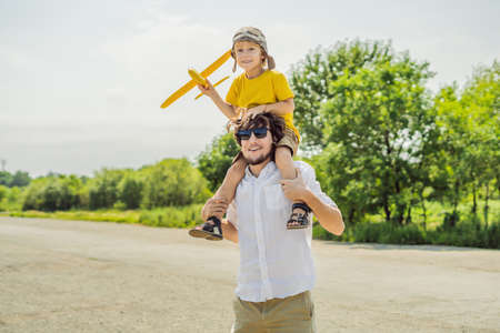 Happy father and son playing with toy airplane against old runway background. Traveling with kids concept.の写真素材
