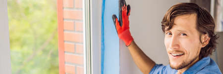 Man in a blue shirt does window installation