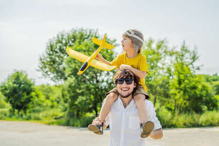 Happy father and son playing with toy airplane against old runwayの写真素材