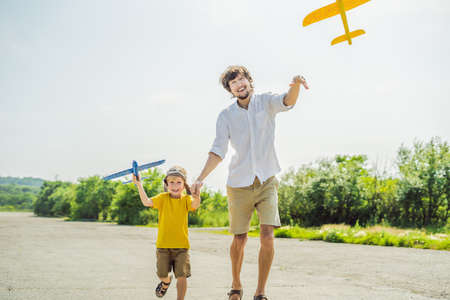 Happy father and son playing with toy airplane against old runway