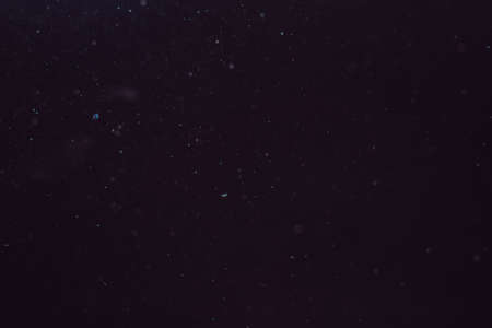 Dust in the air illuminated by light on a dark background.の写真素材