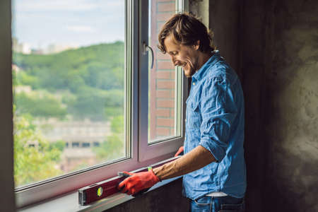 Man in a blue shirt does window installation