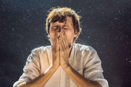 Allergy to dust. A man sneezes because he is allergic to dust. Dust flies in the air backlit by...