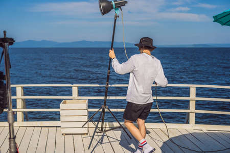 Gaffer or the chief electrician in a motion-picture or television production unit set up the lights and light stand on a commercial shootの写真素材