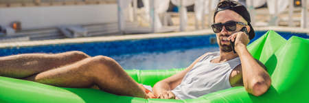 Young man enjoying leisure, lying on the air sofaの写真素材