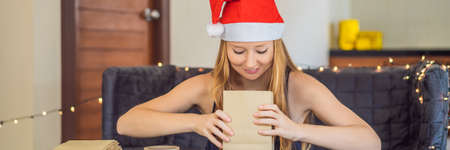 Young woman is packing presents. Present wrapped in craft paper with a red and gold ribbon for christmas or new year. Woman makes an advent calendar for her childの写真素材