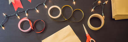 flat lay with christmas present, wrapping paper, ribbon and scissors on a black table. BANNER, LONG FORMATの写真素材