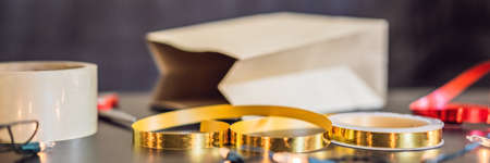 flat lay with christmas present, wrapping paper, ribbon and scissors on a black table. BANNER, LONG FORMATの写真素材