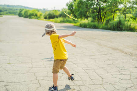 Happy kid playing with toy airplane against old runwayの写真素材