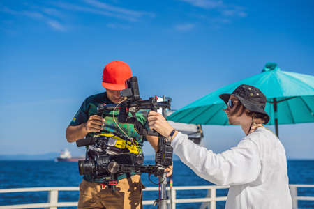 Steadicam operator and his assistant prepare camera and 3-axis stabilizer-gimbal for a commercial shootの写真素材