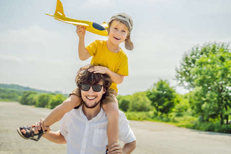 Happy father and son playing with toy airplane against old runwayの写真素材