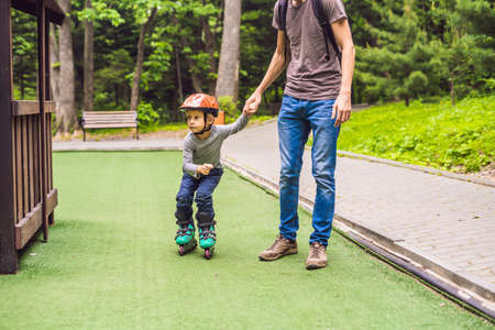 Dad teaches son how to do rollerblading in the park.の写真素材