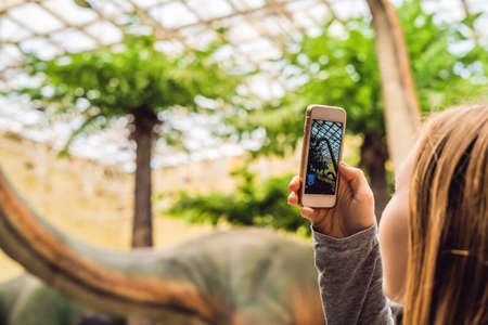 woman use mobile phone and blurred image of people in the dinosaur exhibition.の写真素材