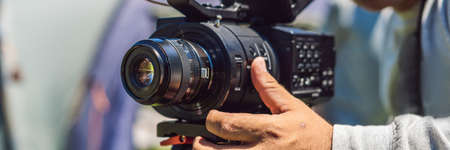 A professional cameraman prepares a camera and a tripod before shooting
