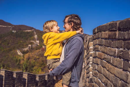 Happy cheerful joyful tourists dad and son at Great Wall of China having fun on travelの写真素材