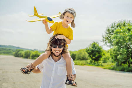 Happy father and son playing with toy airplane against old runwayの写真素材