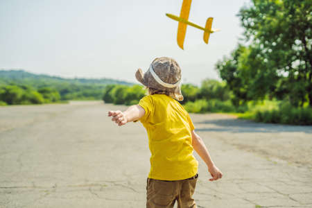 Happy kid playing with toy airplane against old runwayの写真素材