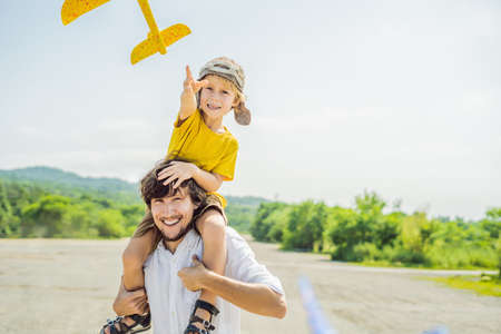 Happy father and son playing with toy airplane against old runway
