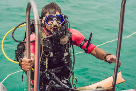 Happy diver returns to the ship after divingの写真素材