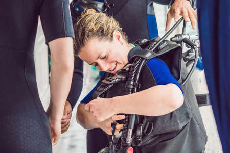 Diving instructor helps a beginner diver prepare for divingの写真素材