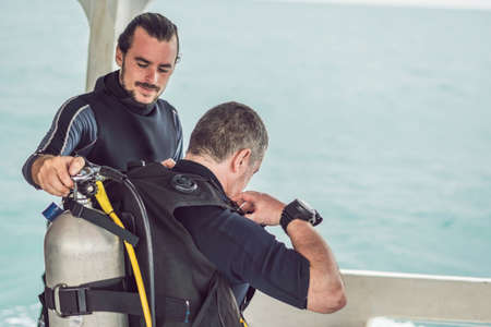 Diving instructor helps a beginner diver prepare for diving
