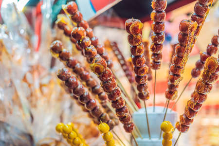 Chinese candied fruits and berries, Hawthorn and strawberries in sesame and sugar syrup. Chinese street food conceptの写真素材