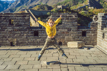 Happy cheerful joyful boy tourist at Great Wall of China having fun on travelの写真素材