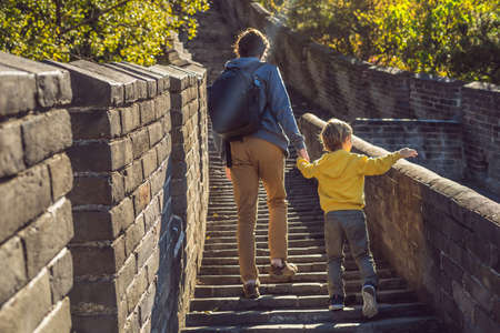 Happy cheerful joyful tourists dad and son at Great Wall of China having fun on travelの写真素材