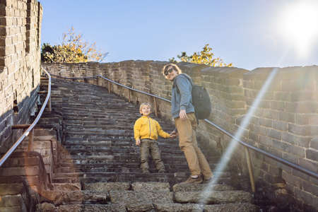 Happy cheerful joyful tourists dad and son at Great Wall of China having fun on travelの写真素材