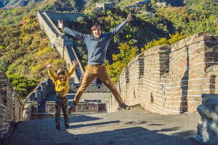Happy cheerful joyful tourists dad and son at Great Wall of China having fun on travelの写真素材