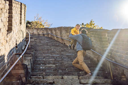 Happy cheerful joyful tourists dad and son at Great Wall of China having fun on travelの写真素材