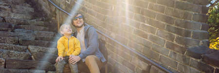 Happy cheerful joyful tourists dad and son at Great Wall of China having fun on travel smiling...
